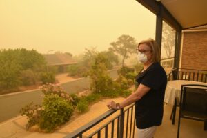 woman-on-balcony-wearing-n95-mask-surveying-smoke